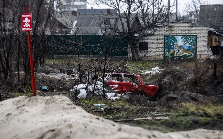 In Lyman, liberated by Ukraine in the counteroffensive, a sign warning of mines stands near a car spray-painted with a “Z,” the symbol of Russian forces.