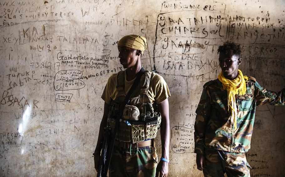 Soldiers stand in an empty jail where al-Shabab is believed to have imprisoned people, in Masjid Ali Guduud. Names and phone numbers were scrawled on the walls. “They thought they were going to die, that’s why they wrote their names,” explained a soldier. 