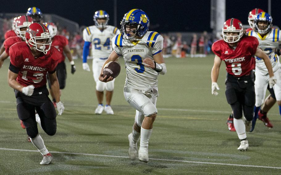 Yokota quarterback Dylan Tomas tries to evade Nile C. Kinnick defenders Justice Rose and Kaito DeMoss.