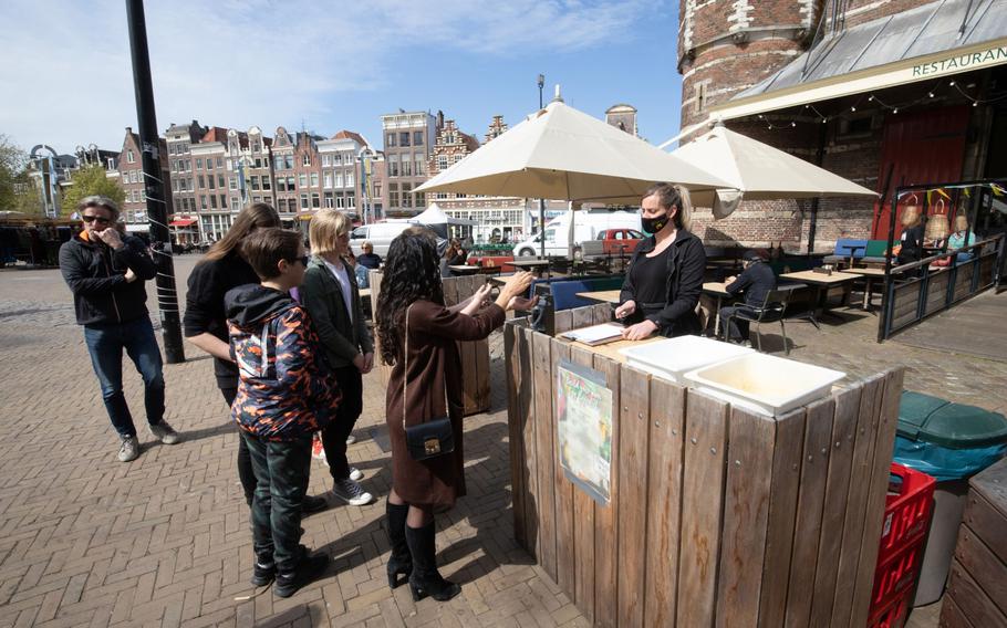 Customers use gel to sanitize their hands before entering a cafe in Netherlands, on April 28, 2021. 