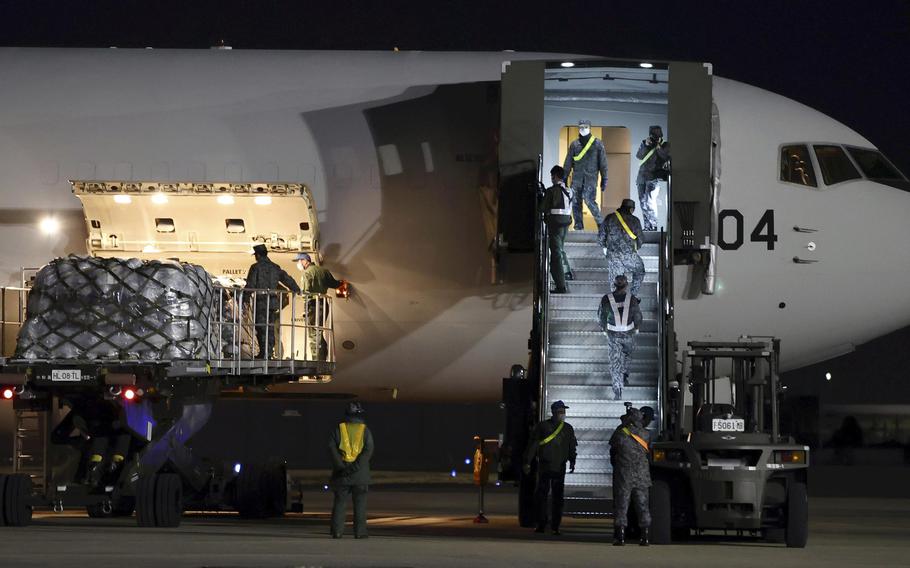 Japan Self-Defense Forces personnel load defense equipment aboard a transport aircraft on Tuesday night at the Air Self-Defense Force’s Komaki Base.