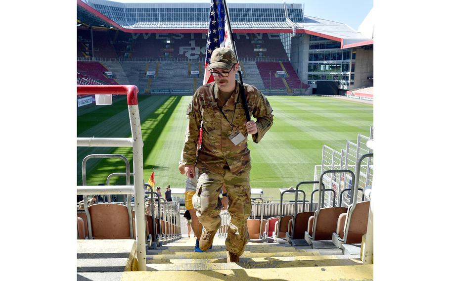 Tech. Sgt. Jonathan Marsh of the 21st Operational Weather Squadron carries an American flag as he climbs the steps of Fritz Walter Stadium in Kaiserslautern, Germany. The city is in the center of the largest overseas U.S. military community, with about 50,000 service members, Defense Department civilians, contractors and family members.