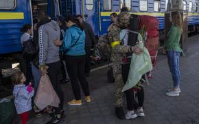 Two couples kiss during their reunion after three months of war-related separation at the Kharkiv train station in eastern Ukraine, Friday, May 27, 2022. (AP Photo/Bernat Armangue)