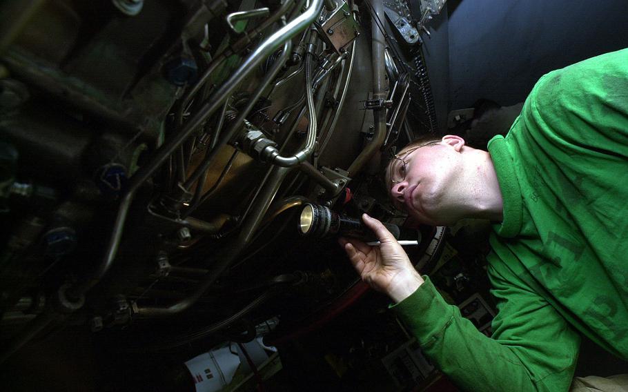 Petty Officer 3rd Class Thomas Bokotey, assigned to VF-154, examines the underbelly of an aircraft in USS Kitty Hawk’s hangar bay Tuesday morning, April 16, 2002, before flight operations.