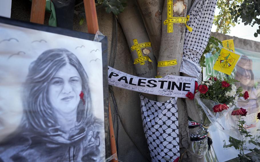 Yellow tape marks bullet holes on a tree and a portrait and flowers create a makeshift memorial, at the site where Palestinian-American Al-Jazeera journalist Shireen Abu Akleh was shot and killed in the West Bank city of Jenin, May 19, 2022. 