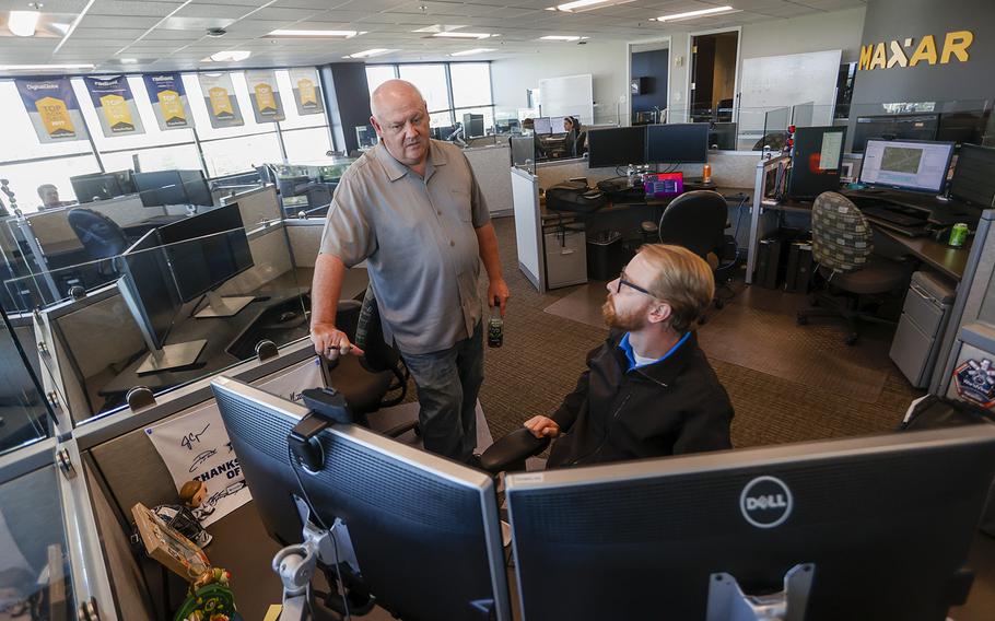 Tampa site director Alex Dunmire, left, and geospatial analyst Kyle Page, right, have a discussion at Maxar’s Tampa office on February 20, 2023.