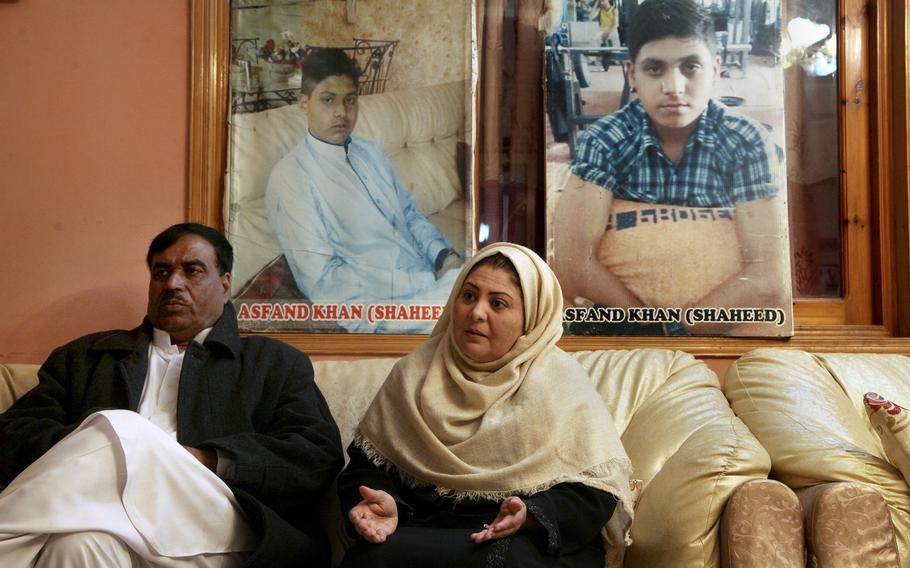 Pakistani mother Shahana with her husband Ajoon Khan sit in their home in Peshawar, Pakistan, on Dec. 29, 2021. next to photos of their son Asfand Khan, who was killed in a 2014 assault by Pakistani Taliban militants on an army public school.