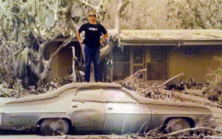 Mark Hanneman, then an agent with the Air Force’s Office of Special Investigations, poses on the roof of an ash-covered car at Clark Air Base, Philippines, following the eruption of Mount Pinatubo in June 1991. 