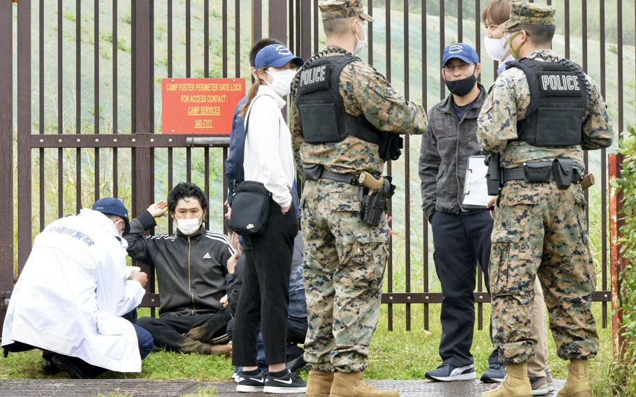 An unidentified man, barefoot and muddy in a black and white track suit, attempted to climb a steel fence within the grounds of Camp Foster, Okinawa, Wednesday, March 2, 2022. 