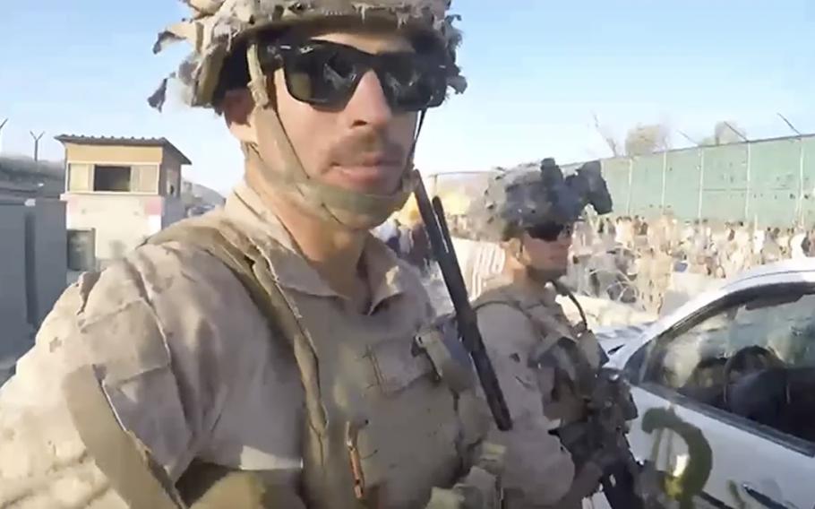 This image from a video released by the Defense Department shows the explosion, behind the two U.S. Marines in the foreground, by a suicide bomber at Abbey Gate outside Hamid Karzai International Airport on Aug. 26, 2021, in Kabul Afghanistan. The military investigation into the deadly attack during the Afghanistan evacuation has concluded that a suicide bomber, carrying 20 pounds of explosives packed with ball bearings, acted alone, and that the deaths of more than 170 Afghans and 13 U.S. service members were not preventable. 