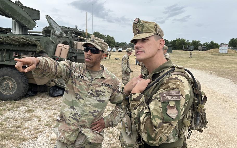 A combat medic talks about his Stryker vehicle with a Hungarian corporal. 