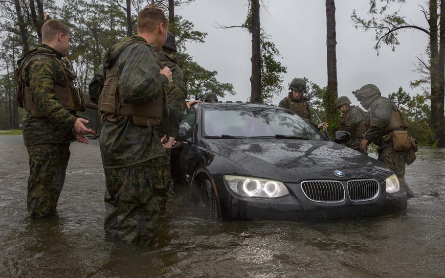 Marines push a car through a flooded area during Hurricane Florence at Camp Lejeune, N.C., in 2018. Climate change poses a challenge for the Navy, the service acknowledged in its recently released climate action strategy.