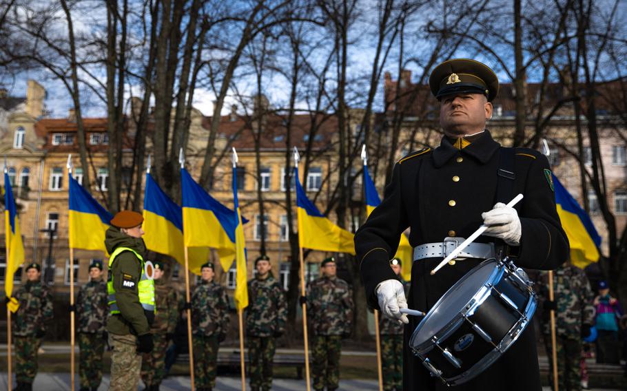 A member of NATO’s enhanced forward presence plays the drums during Lithuania’s NATO Day celebration March 29, 2022. In the background, Lithuanian soldiers hold Ukrainian flags. Lithuania will host Ukrainian troops to prepare them to use weaponry that NATO allies are sending to the fight with Russia, Lithuanian defense officials announced April 10.