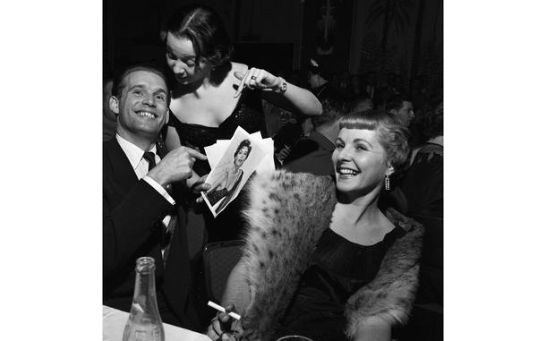 Frankfurt, Germany, February 4, 1954: New York born Puerto Rican actress, dancer and comedienne Olga San Juan jokes around with guests as she tries to entice them to buy raffles to win autographed photographs of Ava Gardner at the March of Dimes benefit held in the main ballroom of the Casino in Frankfurt February 4th, 1954.  The informal show - of which Errol Flynn was the Master of Ceremony - also featured Flynn’s wife actress Patrice Wymore. More than 900 jammed into the main ballroom of the Casino to watch the antics of the star-studded cast and listen to the music supplied by the Air Force’s Sky Tones band. Check out the story and additional photos of the charity event here https://www.stripes.com/news/bacall-package-sold-by-flynn-for-march-of-dimes-1.migrated  META TAGS: Europe; Germany; entertainment; celebrity; March of Dimes; IG Farben building; EUCOM Headquarters