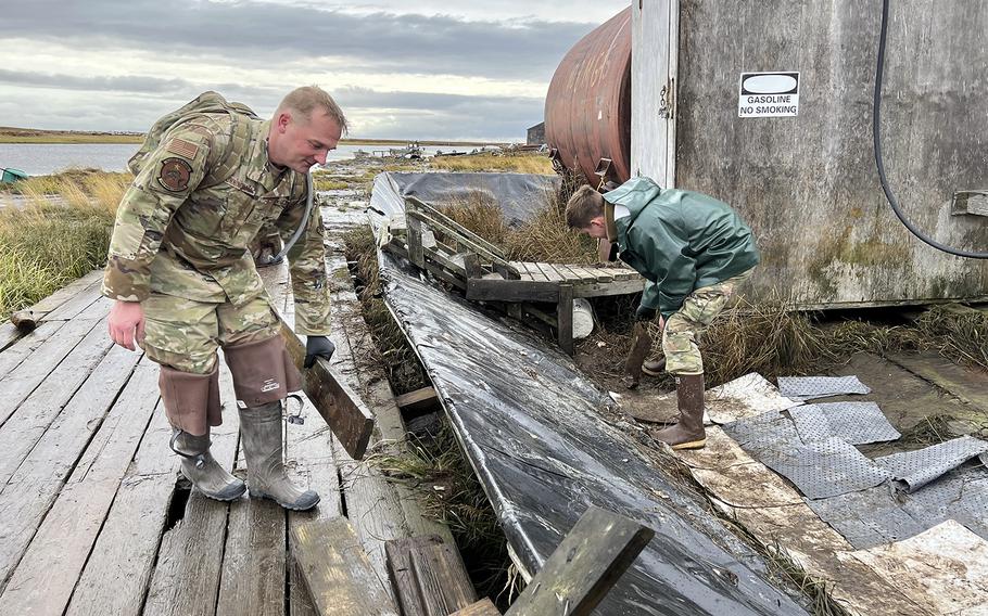 Alaska National Guard Staff Sgt. John Cunningham, left, and Airman 1st Class Reese Halford, both assigned to 176th Wing Maintenance Squadron, of Joint Task Force-Bethel clear storm debris from a boardwalk in Newtok, Alaska as part of Operation Merbok Response, Sept. 22, 2022. 