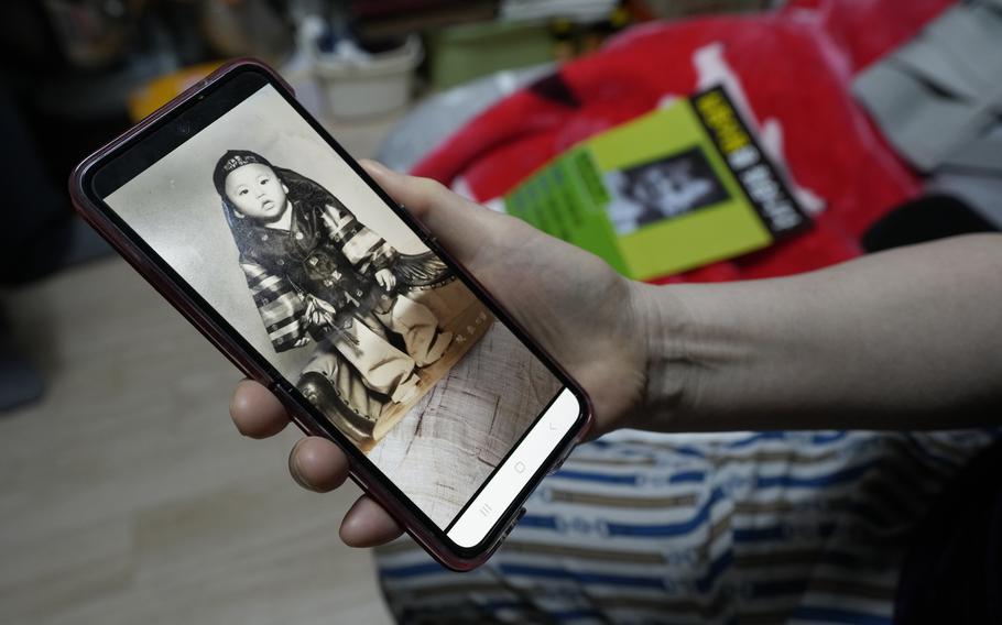 Choi Young-ja holds a smartphone displaying a photo of her son, who went missing in 1975, as she sits in her motel room in Seoul, South Korea, Tuesday, March 5, 2024.