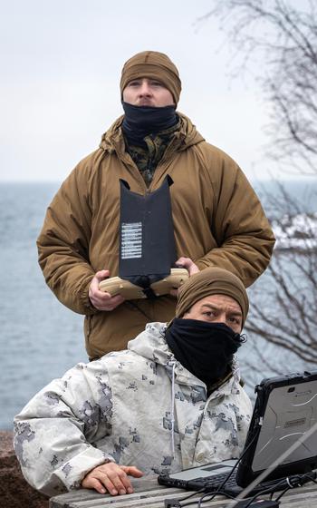 Navy Petty Officer 1st Class Kepono Gowan and Marine Corps Cpl. Blake Hanisak fly an RQ-20 Puma aerial drone.
