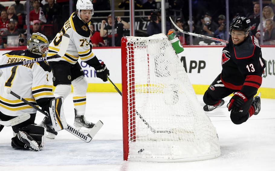 Carolina Hurricanes’ Max Domi (13) dives over the net after getting the puck past Boston Bruins’ Charlie McAvoy (73) and goaltender Jeremy Swayman (1) for a goal during the second period of his team’s 3-2 win in Game 7 Srd
