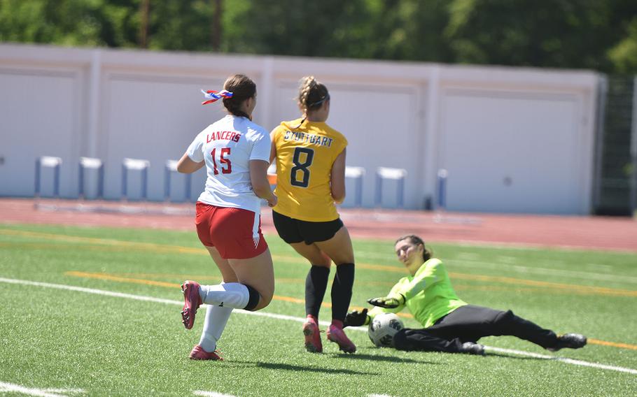 Lakenheath goalkeeper Taylor Gager Clark stops a shot from Stuttgart's Meredith Fleming while Lakenheath's Yulianna Petrich trails the play Monday, May 19, 2025, at the DODEA-Europe Division I girls soccer championships at Ramstein Air Base, Germany.