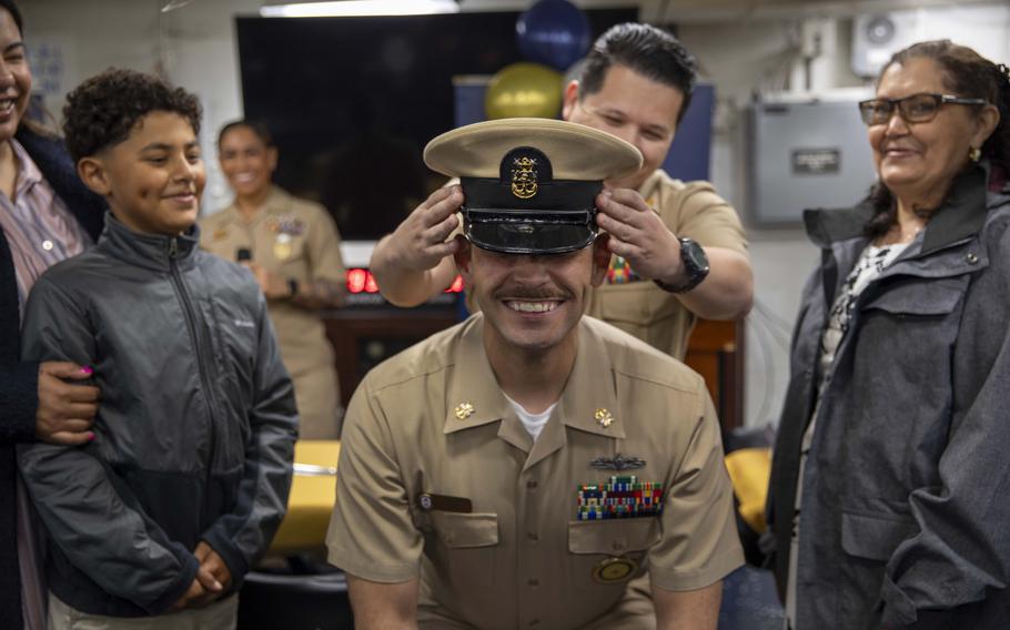 A sailor bends down as he gets promoted to a new a rank
