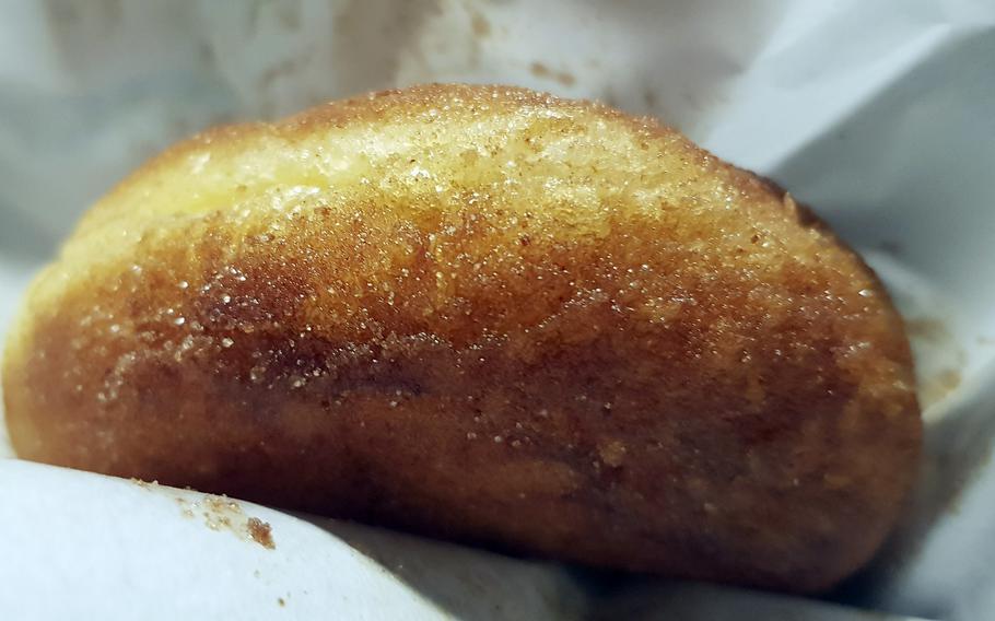 An oblong doughnut rests on a paper wrapping.