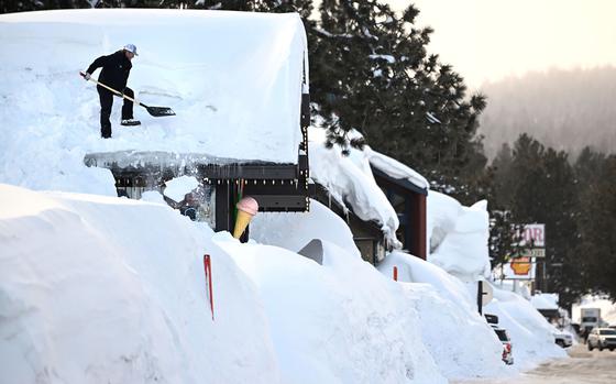 Owner Brang Miller shovels snow off the roof of Mammoth Fun Shop and locals try to dig out in between storms in Mammoth Mountain, Calif., March 7. Usually the Mammoth Mountain ski season lasts from November through June, but this year it will extend into August for only the third time in the resort’s nearly seven-decade history.