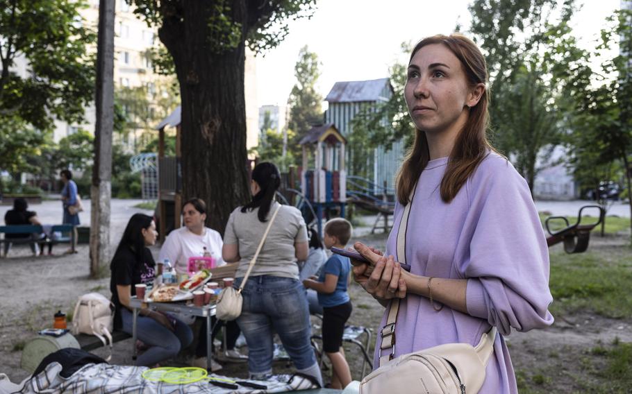 Darya Birukova, a teacher and mother of two, looks at the battle-scarred apartment complex in Dnipro during a picnic with her neighbors last week. 