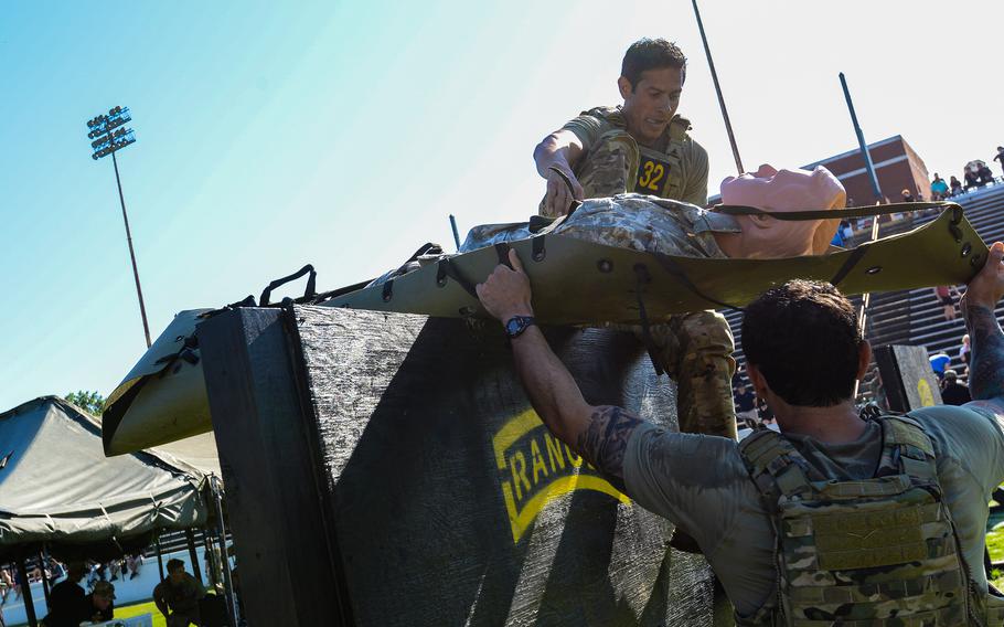 Best Ranger Competition competitors Sgt. Maj. Eric Echavarria and Master Sgt. Charles Gonzalez from the U.S. Army Special Operations Command move a casualty dummy over a 6-foot-high wall during the second day of the competition, Saturday, April 15, 2023, at A.J. McClung Memorial Stadium in Columbus, Ga. 