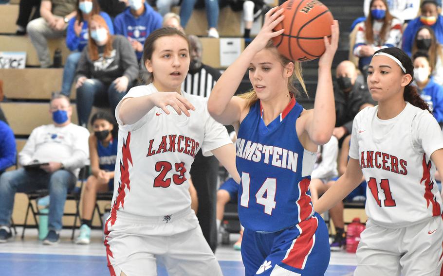 Ramstein’s Spice Harris prepares to kick the ball outside after an offensive rebound on Saturday, Feb. 26, 2022 in the third-place game of the DODEA-Europe Division I girls basketball tournament. Lakenheath’s Eden Wheeler, left, and Laela Britt converge.