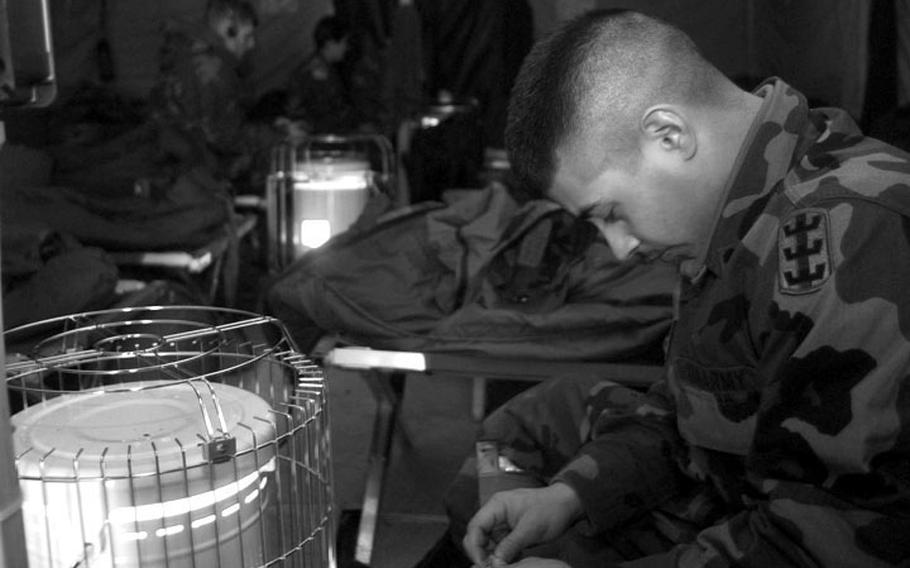 Taszar AB, Hungary, January, 1996: A soldier passes his time reading and staying warm inside his tent before deploying down to Bosnia.