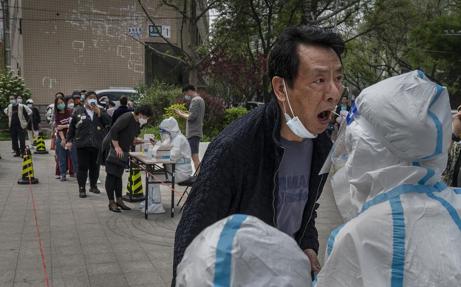 A man is given a nucleic acid test to detect COVID-19 by a health worker at a makeshift testing site in Chaoyang District on April 25, 2022, in Beijing, China. 