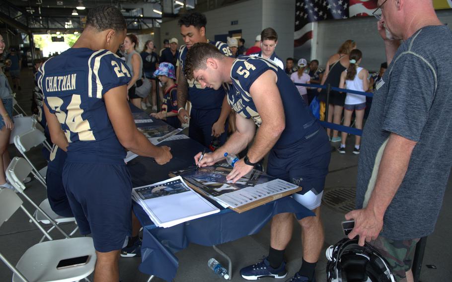 Senior linebacker Will Harbour signs a poster at Navy Football FanFest on July 29, 2023, on the concourse of Navy-Marine Corps Memorial Stadium in Annapolis, Md.