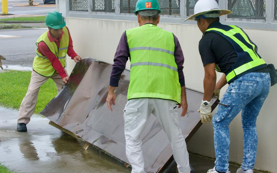 Maintenance workers discard a door from the theater at Camp Foster, Okinawa, Thursday, Aug. 3, 2023. Typhoon Khanun's strong winds broke it off the hinges. 