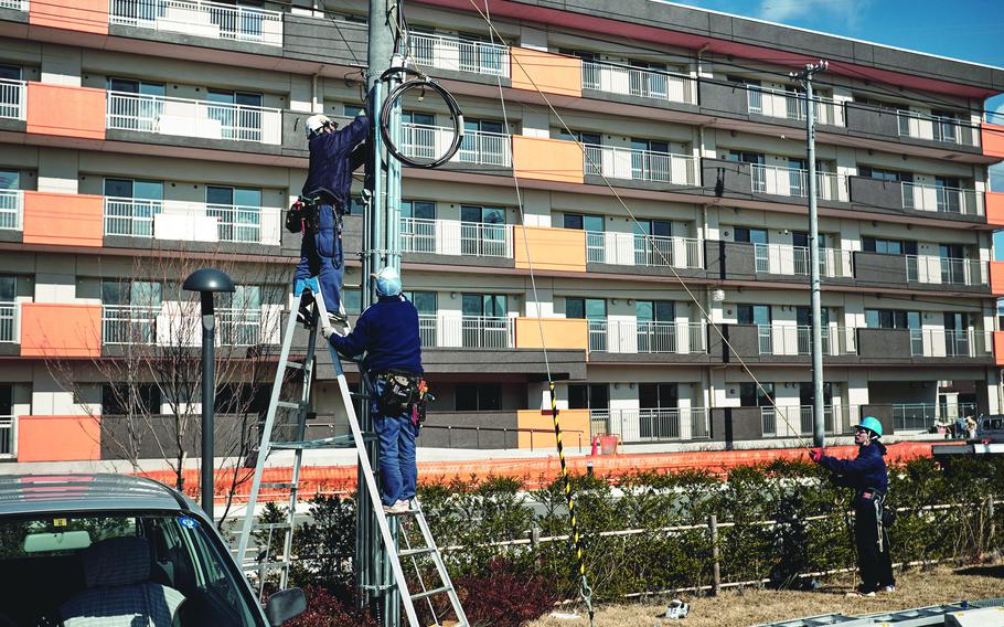 Construction workers raise power lines at a public housing site in Ishinomaki, Japan, Feb. 10, 2016.