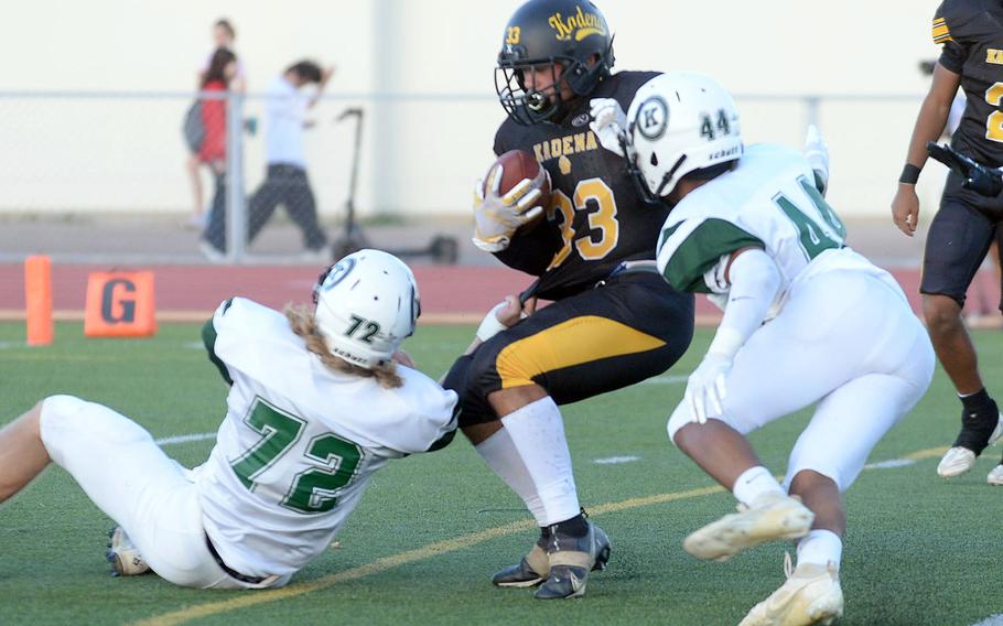 Kadena running back Flint Barton gets bottled up by Kubasaki defenders Kaiser Armour and Trey Johnson.