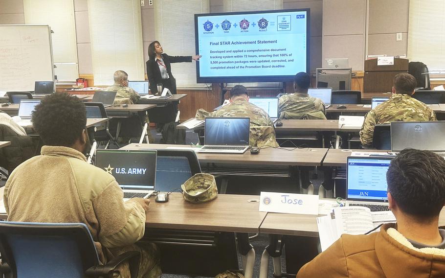 Troops sit at computers in a classroom as they receive instruction.