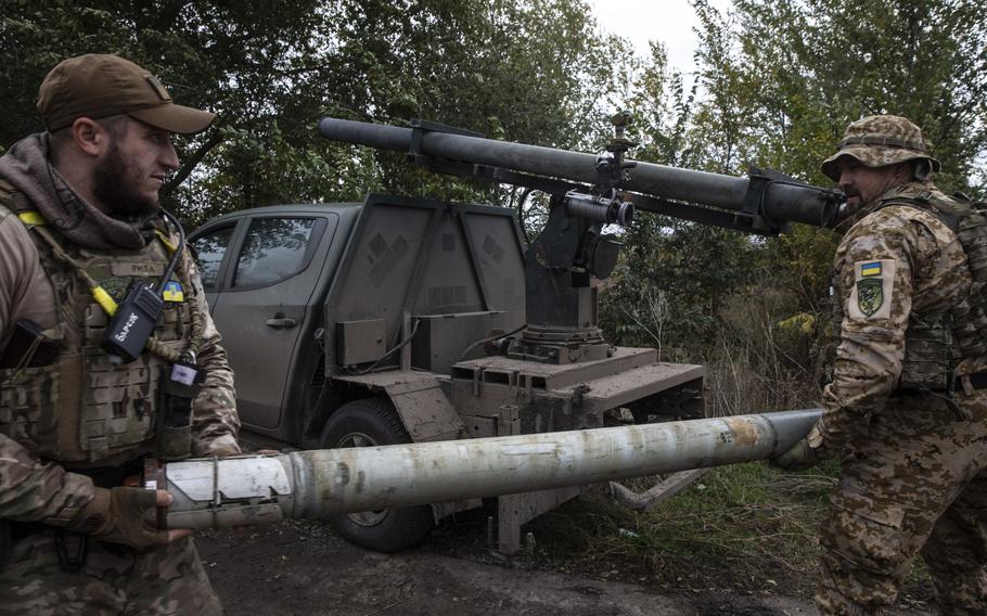 Soldiers in the Karlson unit carry a rocket that they later fired at a Russian position in the Kherson region on Oct. 27, 2022. 