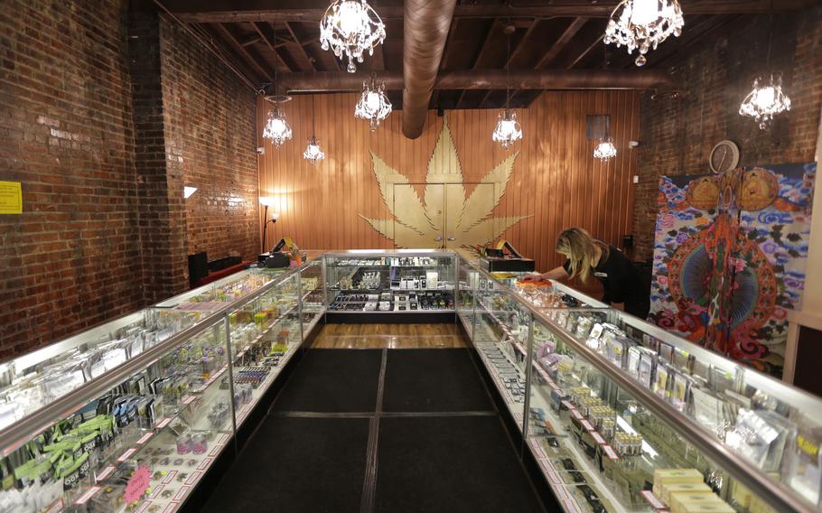 A worker cleans a display case at the Ganja Goddess Cannabis Store in Seattle, on Dec. 7, 2015. Washington state officials announced on June 7, 2021, that the state's nearly 500 licensed marijuana retailers could begin hosting COVID-19 vaccine clinics and offering a single, free pre-rolled marijuana cigarette to any adult over 21 who receives a shot on-site.