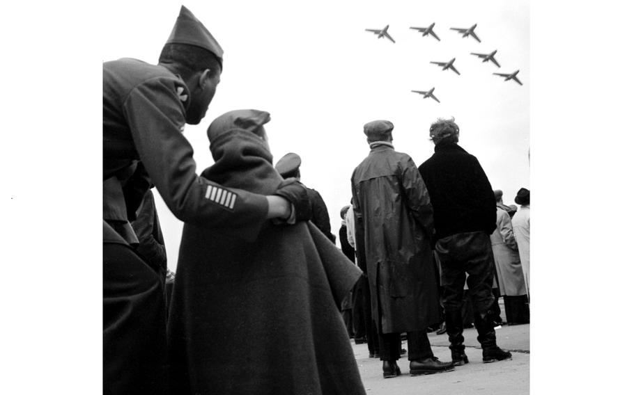 A man and a child look up at airplanes in the sky