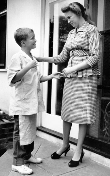 A child greets his mom on a doorstep