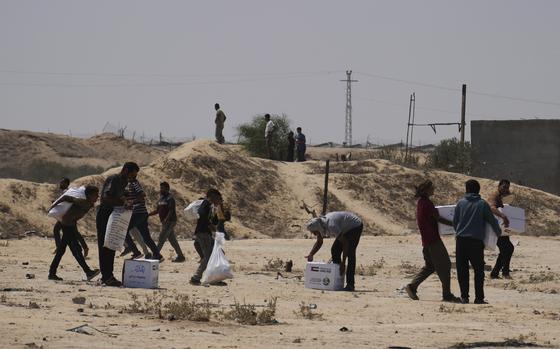 Palestinians collect humanitarian aid packages from the United Arab Emirates after they were airdropped into Deir al-Balah, in central Gaza Strip, Saturday, Aug. 9, 2025. (AP Photo/Abdel Kareem Hana)