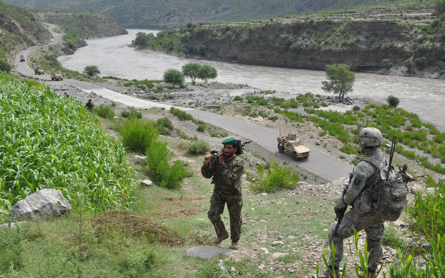 An American soldier looks on as an Afghan National Army soldier makes his way up a mountain beside the main road along the Kunar River at Spin Kay on Aug. 2, 2010. The area is known for insurgent attacks on the U.S. forces that killed 9 U.S. soldiers in a month.