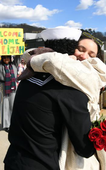 A sailor wraps a woman in an embrace.