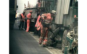 Construction workers attend to a vehicle.