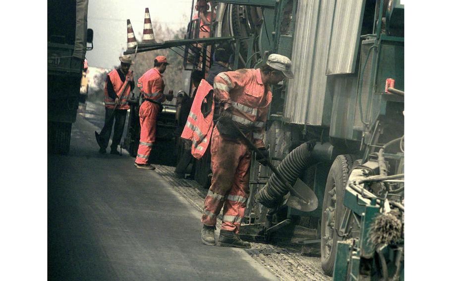 Construction workers attend to a vehicle.