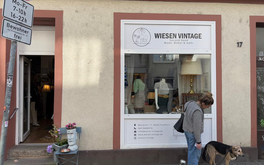 A person with a dog walks by a secondhand store in Frankfurt.
