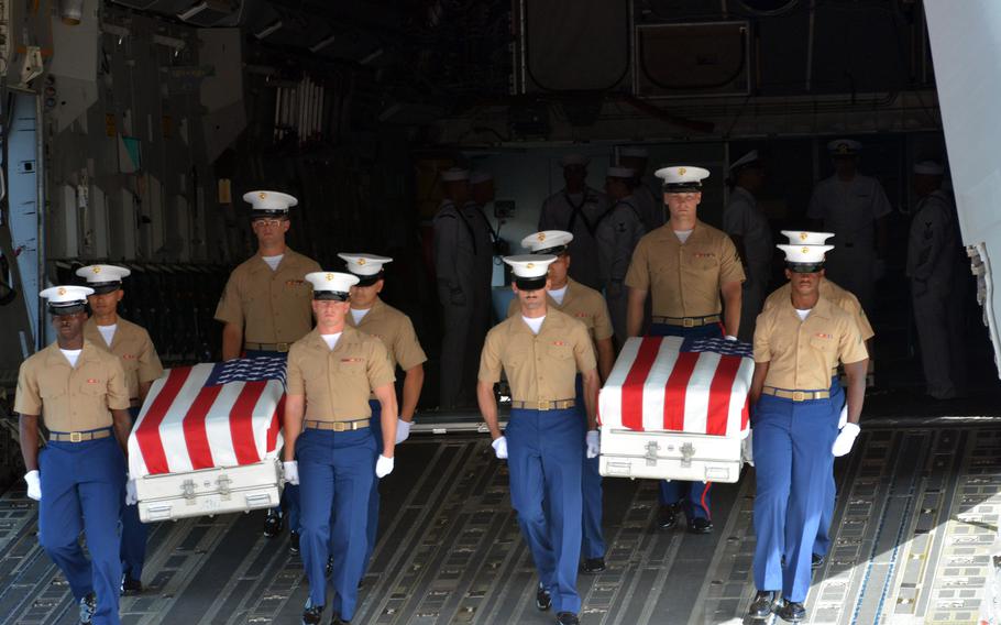 Marines carry coffins from a C-17 during an honorable carry ceremony for the remains of USS Oklahoma service members at Joint Base Pearl Harbor-Hickam, Hawaii, Thursday June 24, 2021.