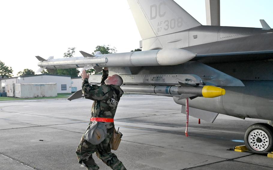 A DC Air National Guard member examines the wing of an F-16.