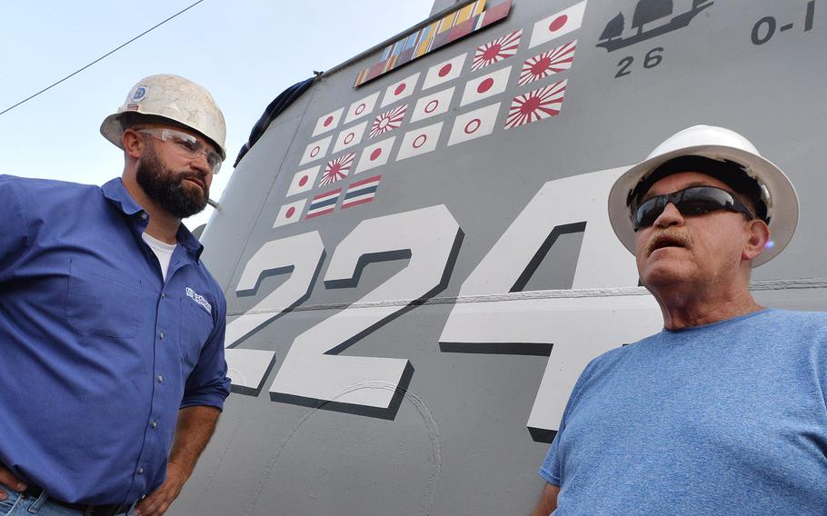 Donjon Shipbuilding & Repair project manager Matt Ross, 40, left, listens as chief of the boat Darrel Flint, 58, describes the enemy flags painted on board the USS Cod on Aug. 11, 2021, in Erie. The floating museum is usually docked in Cleveland and is ending about 6 weeks of steel hull repair and other maintenance.