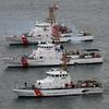 Three Coast Guard ships idle next to each other in open water.